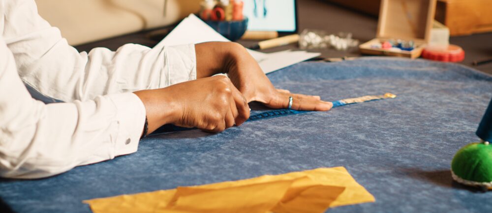 Young tailor using meter on fabric.