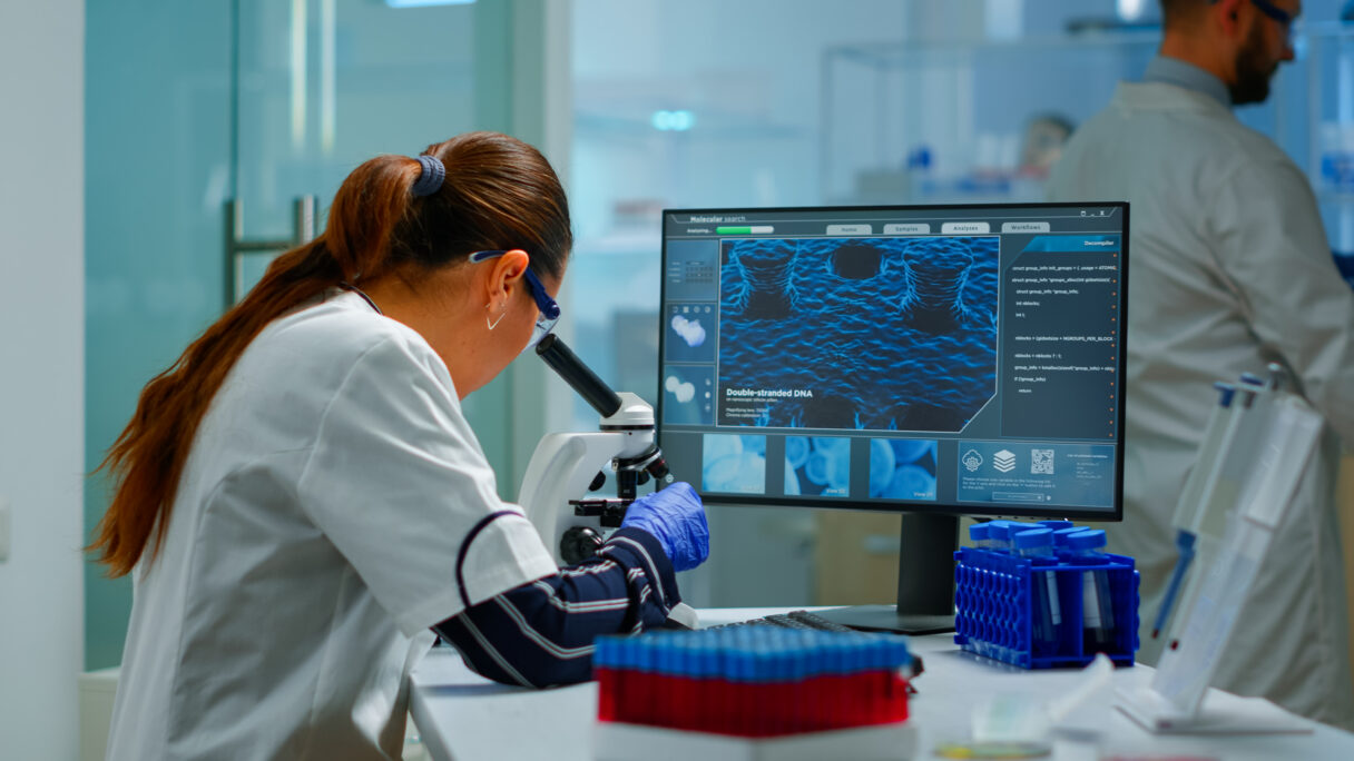 Biotechnology scientist researching in laboratory using microscope.