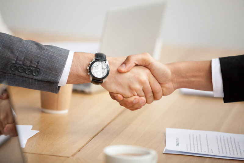 Closeup view of handshake, two businessmen in suits shaking hand.