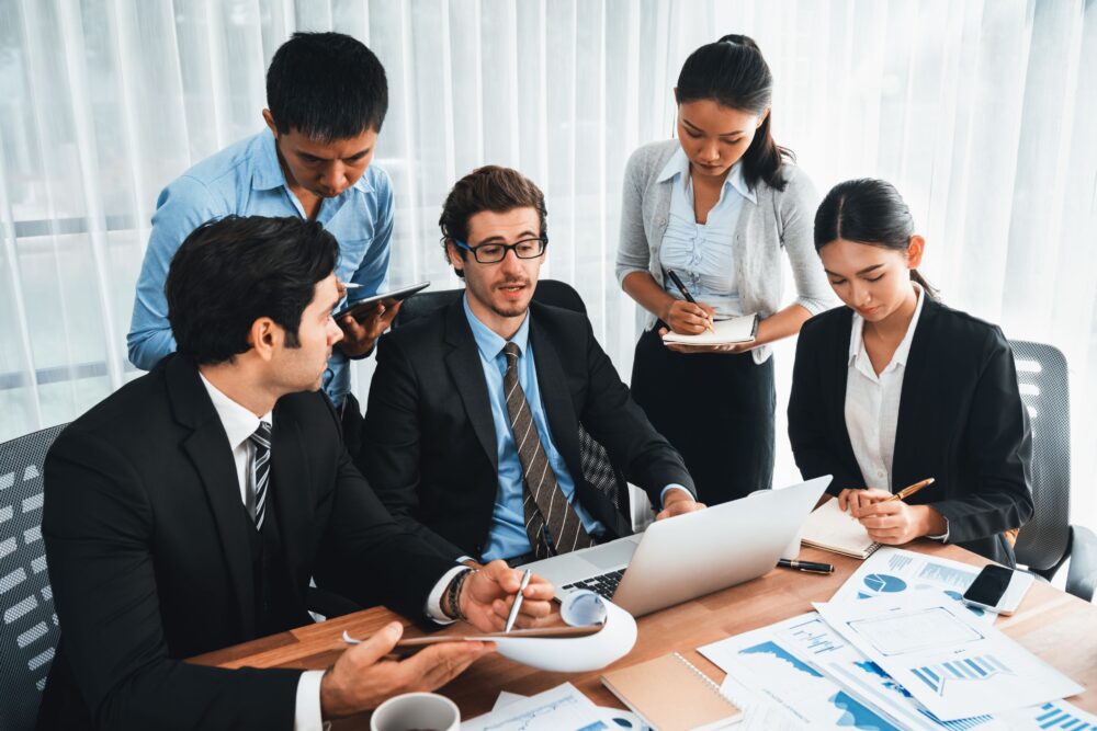 A team of five people speaking with each other about something.