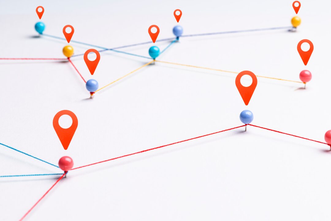 A network of interconnected push pins with red location icons. The pins are connected by colorful strings, forming a web-like structure.