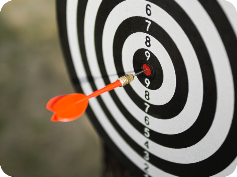 A red dart hitting the bullseye of a dartboard.