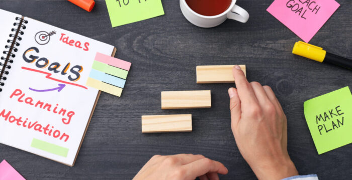 A plan of goals in a notebook on a table with papers.