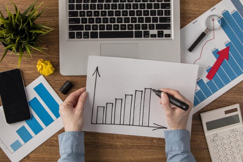 A person is drawing an upward-trending bar graph on a piece of paper. The graph represents growth or improvement.