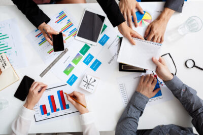 A picture of business people hands on white table with documents and drafts.