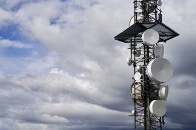 A telecommunication tower against cloudy sky background.